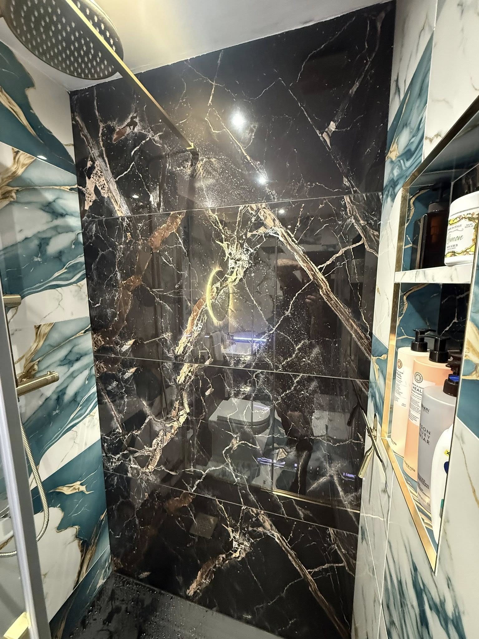 Luxury en-suite bathroom renovation featuring black marble effect tiles and gold fixtures in Blackpool.