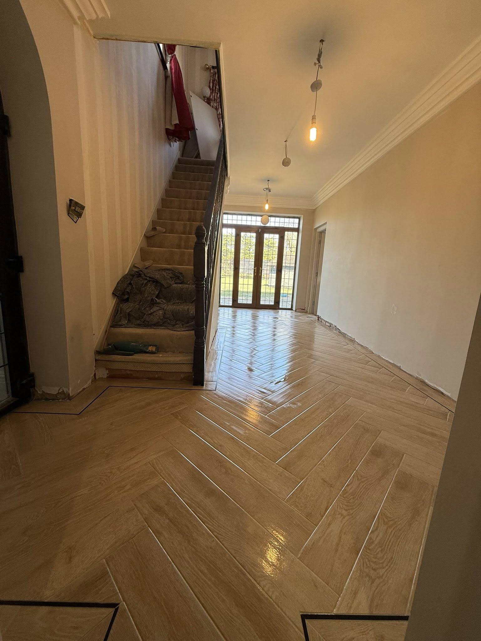 Professional herringbone wood-effect floor tiling installation in a residential hallway by GS Bathroom & Tile.
